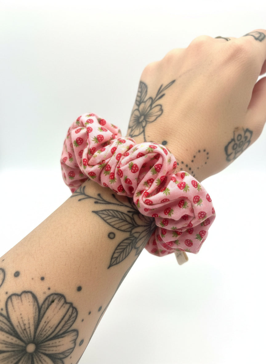 Pink scrunchie hair tie with strawberry pattern on a white background